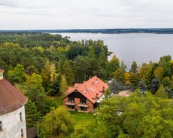 Ośrodek Róża Wiatrów w Węgorzewie to przestrzeń stworzona do wypoczynku nad jeziorem Święcajty. Główny budynek ośrodka oferuje komfortowe zakwaterowanie oraz zaplecze niezbędne do pełnego relaksu w otoczeniu natury. Idealny wybór dla rodzin, par i osób szukających odpoczynku na Mazurach, połączonego z wygodą i pięknymi widokami. Widok na budynek główny ośrodka Róża Wiatrów w Węgorzewie, nad jeziorem Święcajty