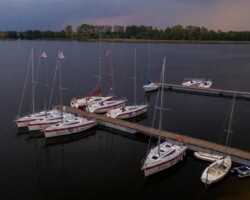 Malowniczy zachód słońca nad jeziorem Święcajty, z widokiem na port i żaglówki w ośrodku Róża Wiatrów Zachód słońca nad jeziorem Święcajty, port i żaglówki w ośrodku Róża Wiatrów w Węgorzewie