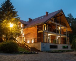 Ośrodek Róża Wiatrów w Węgorzewie to przestrzeń stworzona do wypoczynku nad jeziorem Święcajty. Główny budynek ośrodka oferuje komfortowe zakwaterowanie oraz zaplecze niezbędne do pełnego relaksu w otoczeniu natury. Idealny wybór dla rodzin, par i osób szukających odpoczynku na Mazurach, połączonego z wygodą i pięknymi widokami. Budynek główny ośrodka Róża Wiatrów w Węgorzewie – komfortowe miejsce na wypoczynek nad jeziorem Święcajty