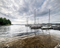 Żaglówki na jeziorze Święcajty widziane z plaży ośrodka Róża Wiatrów – idealne miejsce na wypoczynek nad wodą Widok na jezioro Święcajty i żaglówki z plaży ośrodka Róża Wiatrów w Węgorzewie