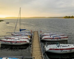 Żaglówki na jeziorze Święcajty widziane z plaży ośrodka Róża Wiatrów – idealne miejsce na wypoczynek nad wodą Widok na jezioro Święcajty i żaglówki z plaży ośrodka Róża Wiatrów w Węgorzewie
