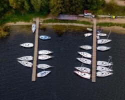 Port żeglarski ośrodka Róża Wiatrów w Węgorzewie to idealne miejsce dla miłośników żeglarstwa i relaksu nad wodą. Przycumowane w spokojnej przystani żaglówki zapraszają do wypraw po jeziorze Święcajty, oferując piękne widoki i możliwość cieszenia się bliskością natury. To doskonała baza wypadowa dla żeglarzy oraz osób szukających wakacji w otoczeniu mazurskich jezior i zieleni. żaglówki przycumowane w porcie ośrodka Róża Wiatrów w Węgorzewie, jezioro Święcajty